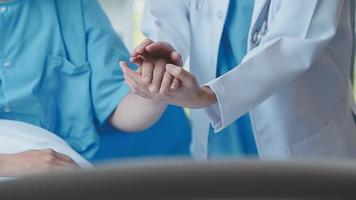 Doctor giving hope. Close up shot of young female physician leaning forward to smiling elderly lady patient holding her hand in palms. Woman caretaker in white coat supporting encouraging old person video