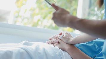 médico dando ter esperança. fechar acima tiro do jovem fêmea médico inclinado frente para sorridente idosos senhora paciente segurando dela mão dentro Palmeiras. mulher zelador dentro branco casaco apoiando encorajando velho pessoa video