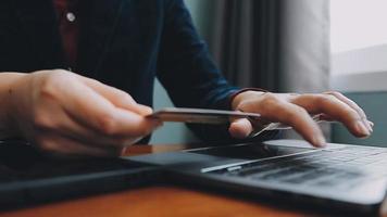 mãos segurando um cartão de crédito e usando o laptop. compras online video