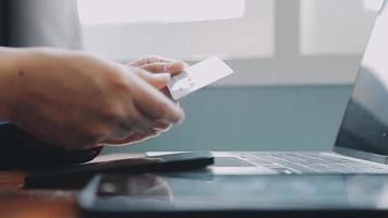 mãos segurando um cartão de crédito e usando o laptop. compras online video