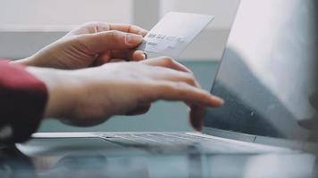 mains tenant une carte de crédit et utilisant un ordinateur portable. shopping en ligne video