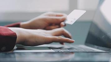 mains tenant une carte de crédit et utilisant un ordinateur portable. shopping en ligne video