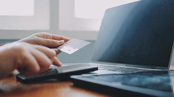 mãos segurando um cartão de crédito e usando o laptop. compras online video