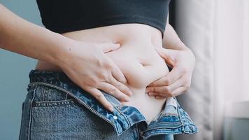 Tummy tuck, flabby skin on a fat belly, plastic surgery concept on gray background video