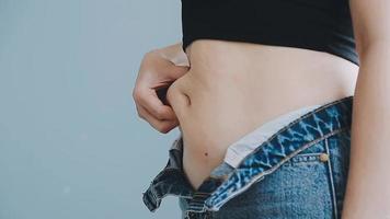 Tummy tuck, flabby skin on a fat belly, plastic surgery concept on gray background video