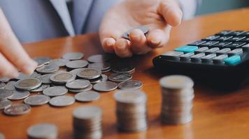 Businessman hand pressing calculator putting coins on pile saving savings for retirement future video