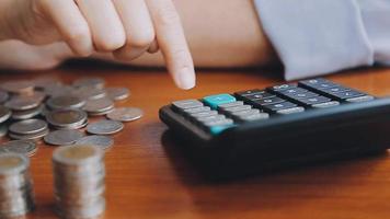 Businessman hand pressing calculator putting coins on pile saving savings for retirement future video