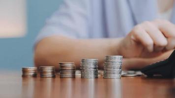 Businessman hand pressing calculator putting coins on pile saving savings for retirement future video