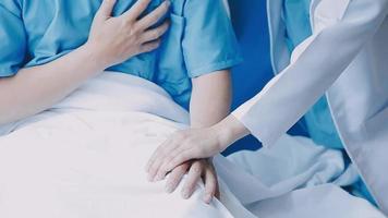 Doctor giving hope. Close up shot of young female physician leaning forward to smiling elderly lady patient holding her hand in palms. Woman caretaker in white coat supporting encouraging old person video