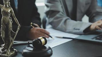 Business and lawyers discussing contract papers with brass scale on desk in office. Law, legal services, advice, justice and law concept picture with film grain effect video