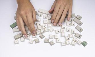 Hands typing with loose keys from a classic office computer keyboard photo