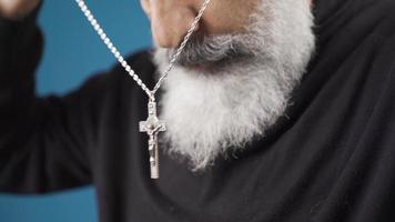 Religious christian man with white beard hangs cross necklace around his neck. The Christian man wears the necklace of the cross around his neck, which means he believes in Jesus Christ. video