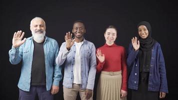 multietnisk grupp av vuxen vänner vinka tillsammans. broderskap och interracial vänskap. grupp av Lycklig multietnisk människor leende och vinka på kamera. video