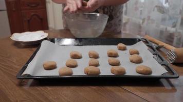 A woman prepares homemade cookies, she puts them on a baking sheet with parchment paper. video