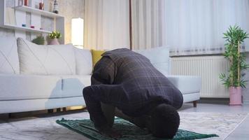 africano musulmano giovane uomo preghiere a casa, adorazione Allah. musulmano onesto e bello africano giovane uomo preghiere solo a casa, appagante il suo dovere per culto il suo Dio. islamico religione concetto. video