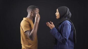 Unhappy muslim african couple arguing and not listening to each other. African muslim couple arguing, fighting and judging each other on black background. video