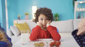 triste chico hojas el mesa mientras su madre y padre son luchando a hogar a desayuno tiempo. video