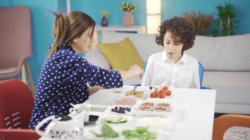 tandis que le mignonne mère et le curieuse enfant sont ayant petit-déjeuner, le enfant demande intéressant des questions à sa mère. video