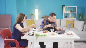 The man who uses a laptop while having breakfast in the morning is surprised by what he sees on the screen and his wife is included in his joy. video