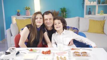 Happy and candid portrait of parents and their son. Happy and cute family having breakfast at home looking at camera and smiling. video