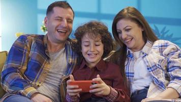 Young mother and father with their sons resting on the sofa, spending time together. Portrait of a happy beautiful family with their boys sitting on the sofa and having a cheerful and pleasant time. video