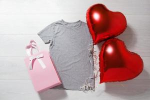 gris camiseta Bosquejo. san valentin día concepto camisa, globos corazón forma en de madera antecedentes. Copiar espacio, modelo blanco frente ver camiseta ropa. romántico atuendo. plano laico cumpleaños fiesta Moda foto