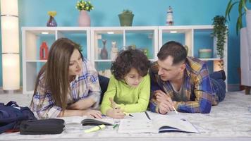 gelukkig familie ouders helpen hun weinig jongen met zijn lessen. de gekweekt en modern familie ouders helpen hun zonen met hun lessen Bij huis. video