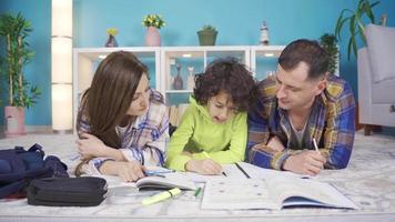 moeder en vader Doen hun zonen huiswerk schrijven en lezing Bij huis, ze helpen. onderwijs en opleiding concept. video