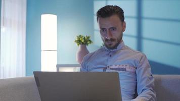 à moda elegante homem trabalhando remotamente às dele casa às noite usando computador portátil. bonito à moda vestido homem trabalhando dentro casa escritório usando computador portátil enquanto sério e focado. video