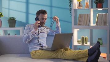 Handsome and charismatic businessman looking at laptop and making serious phone call. Businessman executive working remotely on laptop, doing business online, making phone call. video