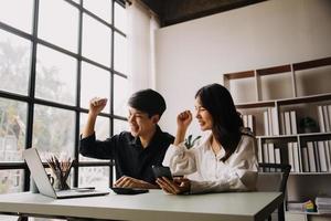 grupo de jóvenes empresarios asiáticos del equipo de negocios creativos compañeros de trabajo en el cargo felices de tener éxito en el trabajo en equipo de la asociación celebrando el logro y el concepto de éxito. foto