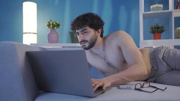 nu Jeune homme en utilisant portable ordinateur dactylographie quelque chose sur clavier, en train de préparer texte, SMS, Envoi en cours poster.