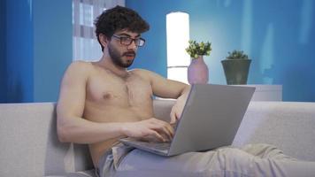 Naked young man using laptop typing on keyboard serious and focused. Focused young man using laptop, getting things done, preparing important reports, mailing. video