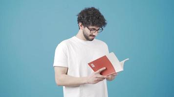 colto giovane uomo lettura un' libro assunzione via il suo bicchieri e sorridente a telecamera per incoraggiare lettura. il intelligente e colto giovane uomo gode lettura e è contento. lettura, essere un' alunno. video