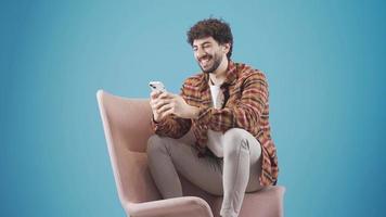 casual vestido joven hombre mensajes de texto utilizando teléfono inteligente adentro a hogar. moderno dispositivos y comunicación concepto. video