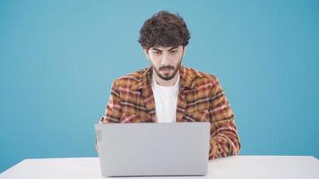 jovem homem usando computador portátil às mesa digitando em teclado sério e focado. focado jovem homem usando computador portátil, obtendo coisas feito, preparando importante relatórios, enviando. video