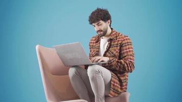 sonriente joven hombre disfrutando simpático comunicación utilizando ordenador portátil. joven hombre utilizando ordenador portátil computadora mecanografía alguna cosa en teclado, preparando texto, enviar mensajes de texto, enviando correo. video