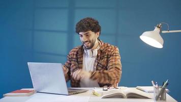 jovem aluna homem completando dele dever de casa ou uma criativo projeto e experimentando alegria. jovem homem trabalhando Difícil e gastando energia completando computador portátil. video