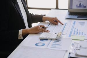 Woman accountant use calculator and computer with holding pen on photo