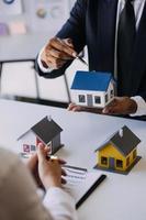 House model with real estate agent and customer discussing for contract to buy house, insurance or loan real estate background. photo