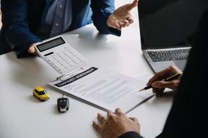 A car rental company employee is handing out the car keys to the renter after discussing the rental details and conditions together with the renter signing a car rental agreement. Concept car rental. photo