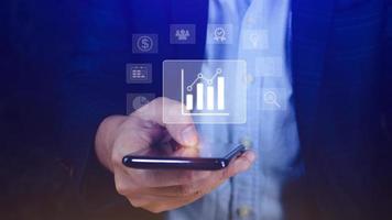 Data analytics and business intelligence BI concept with chart and graph icons on digital screen interface on smartphone and business people in the background. photo