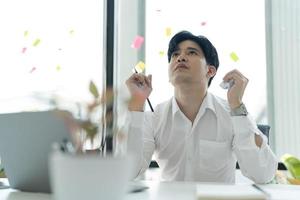 Young businessman sitting at his desk looking at the internet on his laptop Feeling stressed. photo