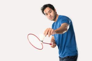 A badminton player in sportswear stands holding a racket and shuttlecock.
