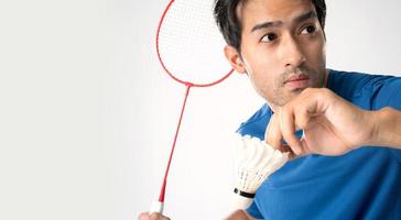 A badminton player in sportswear stands holding a racket and shuttlecock.