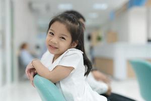 niña sentado sonriente en el hospital vestíbulo. foto