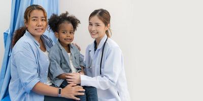 el niña se sienta en el del paciente cama para el doctor. foto