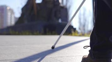 The visually impaired man is walking. Close-up shot of his walking stick and feet. Close-up shot of blind man's feet and walking stick. He is walking on the road with the help of his cane. video