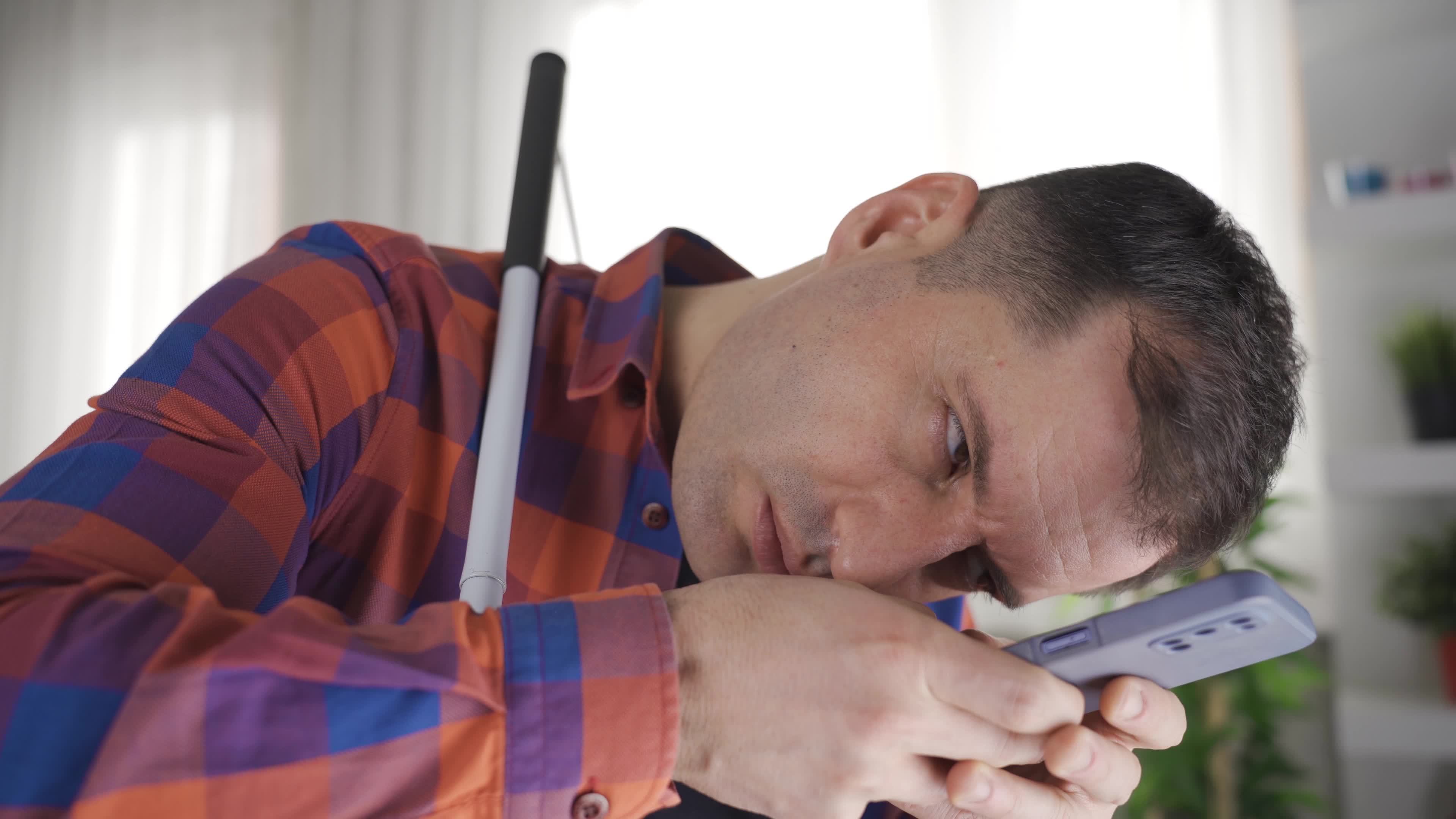Blind man looking at phone, myopia. Blind man with very close vision, looking at the phone