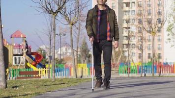 blind Mann mit Weiß Stock Gehen auf das Straße. blind Mann Gehen auf ein Pfad durch das Spielplatz. video